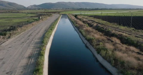 Close-up aerial fly over view of an irrigation canal on a large vegetable farm Stock Footage 253877839