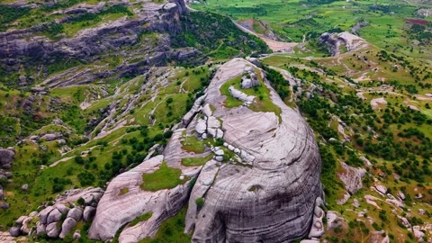Close Aerial Orbit Around a Massive Rock Formation in a Green Valley Stock Footage 341273422