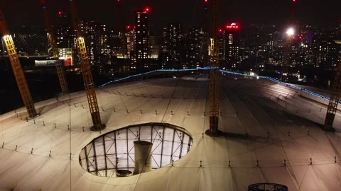 Close aerial pan of O2 Arena at night with London skyscrapers in background Video stock 302914985