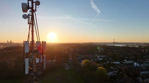 Close aerial pass of telecom mast through sunrise flare Stock Footage 331206789