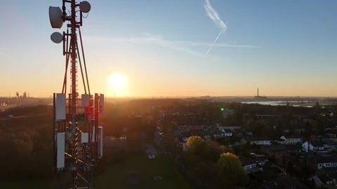 Close aerial pass of telecom mast through sunrise flare Stock Footage 340938989