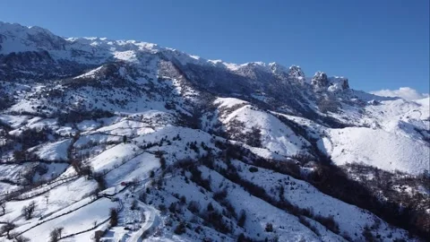 Close-up aerial of a snow-capped mountain with trees in Asturias. Angliru. Stock Footage 152134844