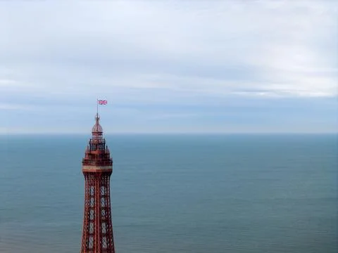 Close aerial view of Blackpool Tower top with Union Jack flag and sea backg.. Stock Photos