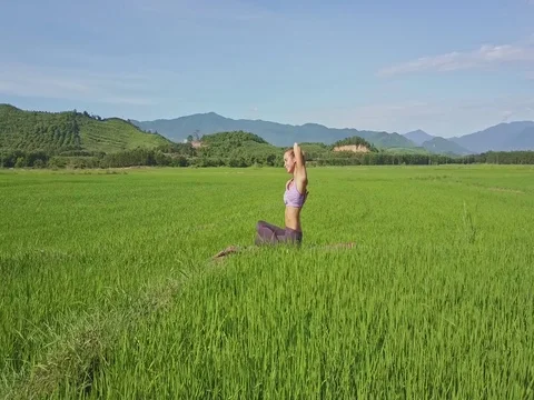 Close Aerial View Girl Sits in Yoga Pose on Mat against Hills Stock Footage