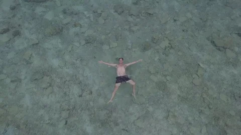 Close up aerial view of man floating on the water in blue ocean and camera tr Stock Footage 105214091
