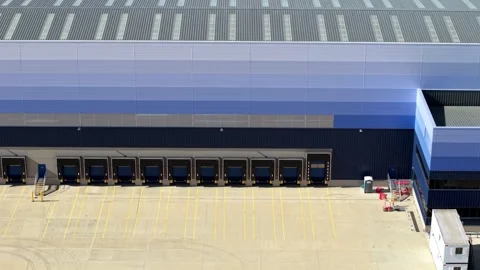 Close-Up Aerial View of Modern Warehouse Loading Bay Doors and Concrete Yard Stock Footage 343921465