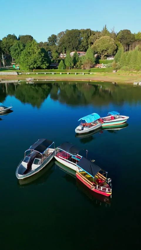 Close aerial view of moored tour boats with canvas canopies on a calm lake Stock Footage 346014872