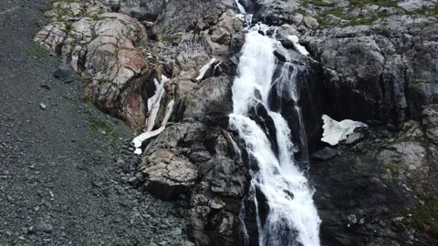 Close up aerial view of powerful mountain waterfall with melting snow patches Stock Footage 335093745