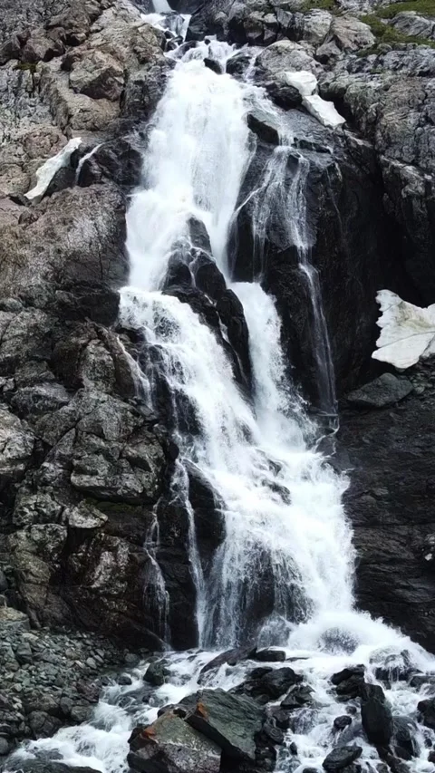 Close up aerial view of powerful mountain waterfall with melting snow patches Stock Footage 336685040