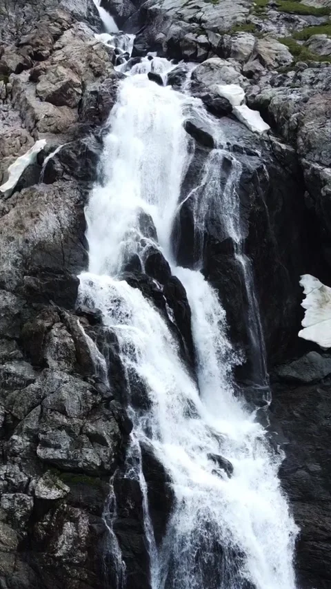 Close up aerial view of powerful mountain waterfall with melting snow patches Stock Footage 336685052