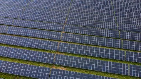 Close aerial view of rows of solar panels on green field Stock Photos