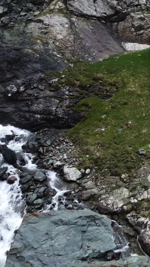Close up aerial view of rushing white water stream and rugged rocks with moss Видео 336691831