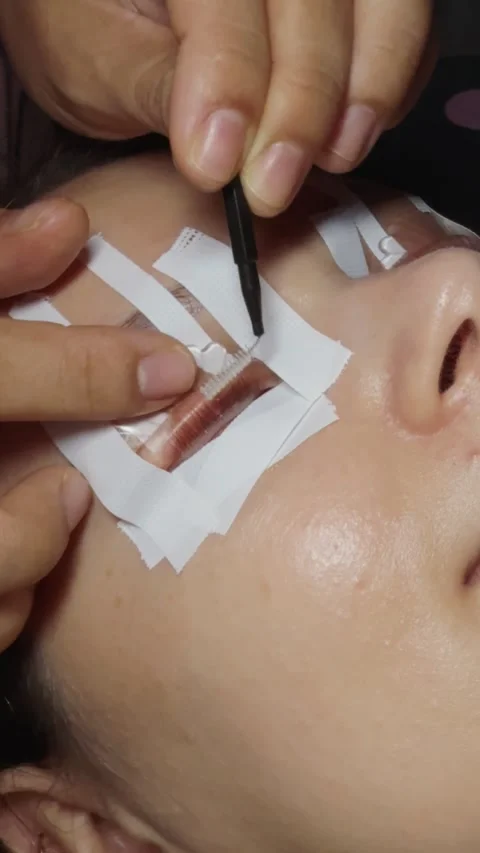Close up of an aesthetician performing a lash lifting and perm procedure on a Stock Footage 332806489