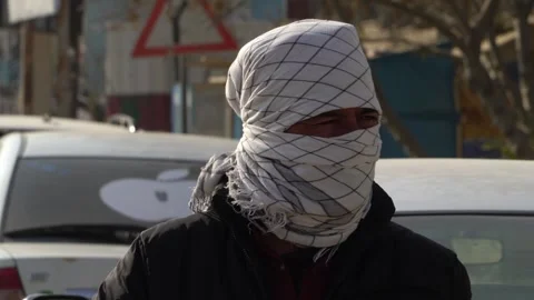 Close-up of Afghan man outdoors with patterned scarf covering his face Video stock 240913651