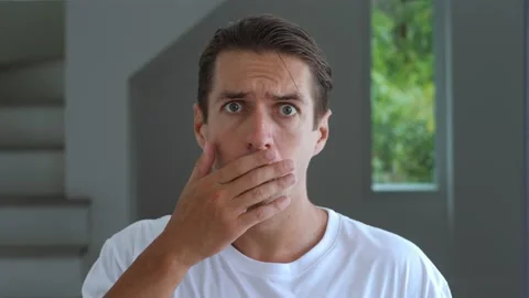 Close-up afraid millennial business man staring eyes and covering mouth in Vidéo 239542892