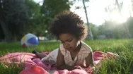 Close Up Of African-American Girl Lies In The Park On The Bedspread And Watches Stock Footage