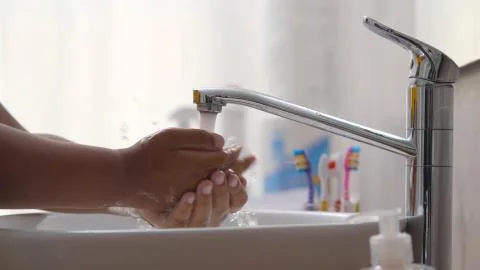Close up of african child using liquid soap and washing hands in bathroom Stock Photos