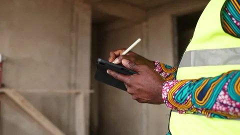 Close-up, African construction engineer uses tablet and stylus on site Stock Footage 346258312