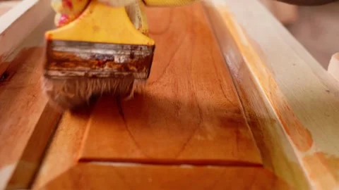 Close-up, African male carpenter applying oil-based wood polish with a brush Stock Footage 346733896