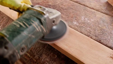 Close-up of African male carpenter using angle grinder to sand wooden plank Stock Footage 346733752