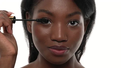 Close up of an african woman's face. Applying mascara on her eyelashes. White Stock Footage 156603426