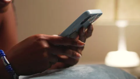 Close-up of an African woman's hands holding a smartphone, and typing. Video stock 345609225