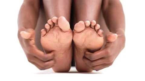 Close up of an African woman's hands scratching her feet and soles. Isolated on Stock Footage 160672387