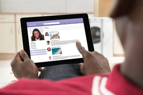 Close-up Of African Young Man Chatting On Social Networking Site Using Digita Stock Photos