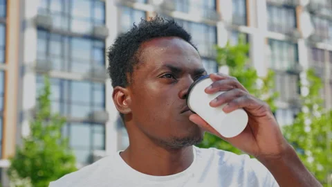 Close up afro-american man freelancer drinks coffee or tea from white paper cup Stock Footage 157447175