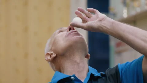 Close Up of Aged Man Attempting Trick with Tennis Ball Using Air Stock-Footage 319184434