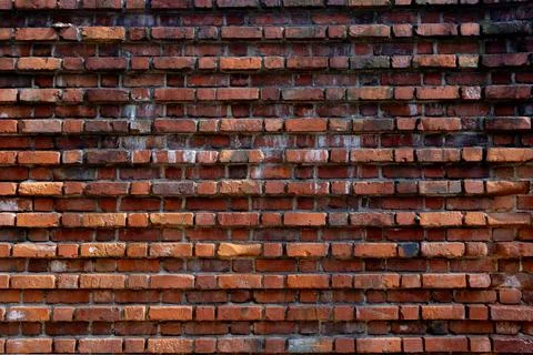 Close-up of an aged red brick wall with dark mortar and weathered texture. Stock Photos