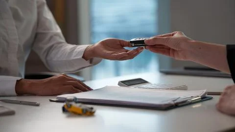 Close up of agent passing car key to customer across desk after contract Stock Photos