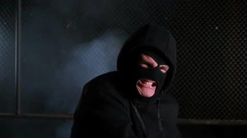 Close up. An aggressive man in a balaclava and hood hits a baseball bat in front Stock-Footage 169478600