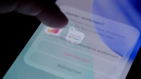 Close-up of the Agoda app being deleted from a smartphone home screen in a dark Stock Footage 337240568
