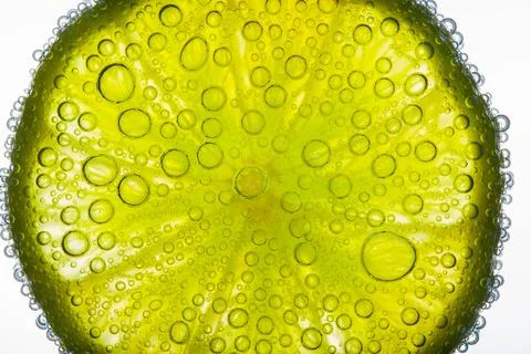 Close-up of air bubbles covering slice of juicy lime floating in Stock Photos
