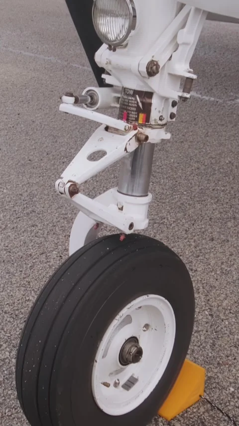 Close-up of airplane front landing gear wheel secured on airport tarmac, Vidéo 338378849