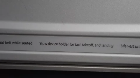 Close-up of an airplane seat back displaying safety instructions including Stock Footage 340562795