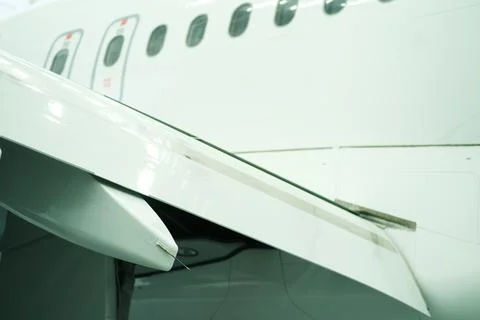 A close-up of an airplane wing and engine at an airport. The aircraft appears Stock Photos