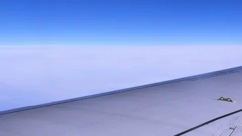 Close-up of an airplane wing during a flight in a blue clear sky Stock Footage 106061130