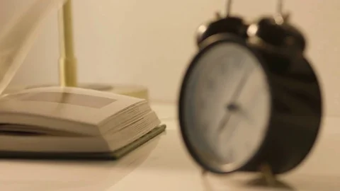 Close up of an alarm clock beside a book Video stock 78190945