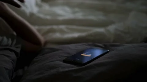 Close up of alarm clock on a digital cell phone display waking up a man in bed Stock Footage 139742793