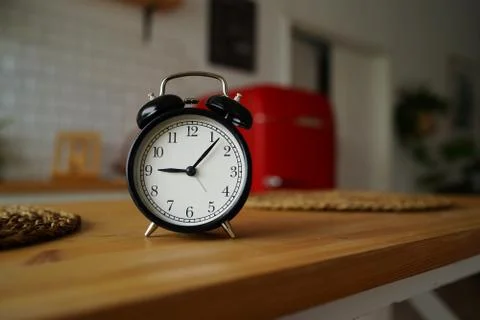 Close up of alarm clock on table in kitchen. Black vintage clock on kitchen t Stock Photos