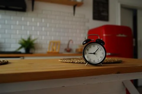 Close up of alarm clock on table in kitchen. Black vintage clock on kitchen t Stock Photos
