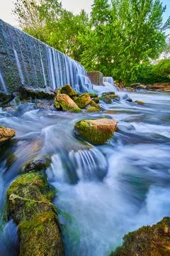Close to algae rocks sticking out of waterfalls by manmade dam 스톡 사진