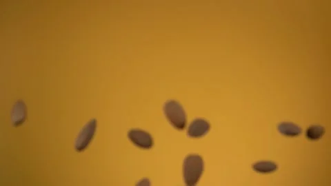Close up of almonds bouncing and rotating on the yellow background Stock Footage 131016810