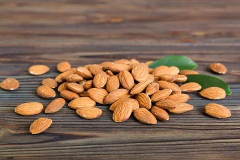 Close-up of Almonds nuts with leaves on table background. Top view. Flat lay Stock Photos