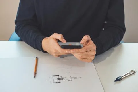 Close-up of an ambitious architect looking to a mobile phone for inspiration  Stock Photos