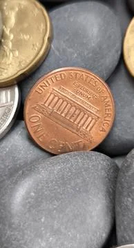 Close up of American one cent copper coin lying on grey pebbles 스톡 사진