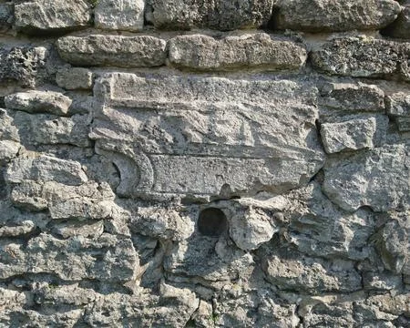 Close-up of ancient stone wall texture with a decorative carved stone block Stock Photos