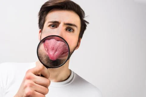 Close up and cut view of a guy showing his tongue through the loupe. He is tr Stock Photos